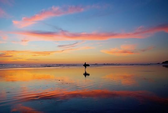 Surfer walking on the beach after sunset