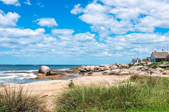 Boulders, green grass, and seaside houses at Punta del Diablo, a popular beach in Uruguay