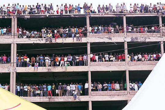 Rwandans lining the floors of an empty, open building to watch a cycling race