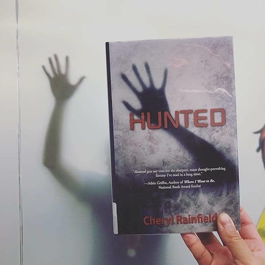 I LOVE this creative #bookface that @tulsalibrary made with HUNTED. (beaming) I had thought that readers wouldn’t be able to do #bookface with my books because they don’t have faces, but @tulsalibrary was so creative, smart, and playful about it! <br />Via @tulsalibrary – How’s this for a #bookface on this dreary Friday? Featuring YA novel ‘Hunted’ by @cherylrainfield<br /><br />#bookstagram #YAlit #YAbooks<br />#cherylrainfield #YAwriter #LGBTQwriter #booknerd #bookworm #ireadYA #survivor #feminist #YAlit #yafantasy #yafantasybooks