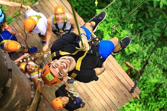 Man in a harness in a jungle ropes course
