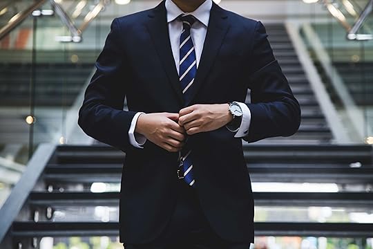 Man with tie in front of stairs buttoning suit jacket