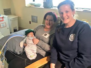 photo of NICU baby, Liam, his mum, and a student who helped to knit the hats