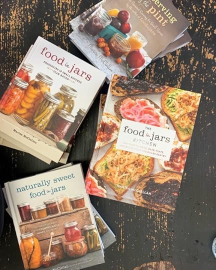 Stacks of Food in Jars, Preserving by the Pint, Naturally Sweet Food in Jars, and The Food in Jars Kitchen arranged on a chipped black table.