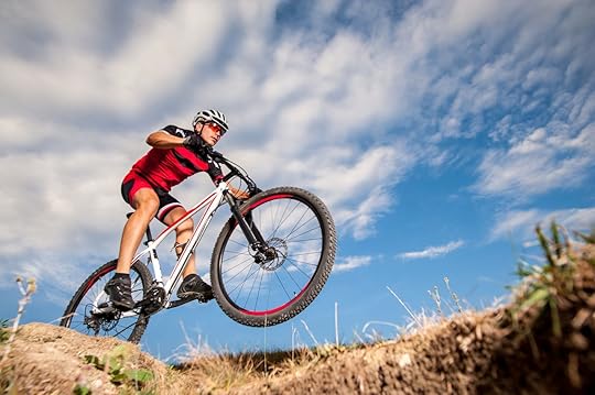 Low angle, wide angle portrait against blue sky of mountain biker going downhill