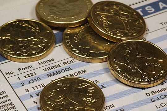 Dollar coins spread out over a horse racing form