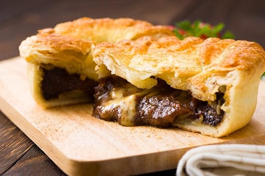 Flaky, juicy meat pie on a wooden cutting board