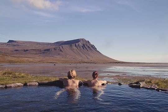 Happy couple in love bathing and relaxing in hot pool with spectacular view of wild landscape
