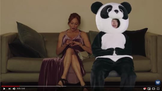 Ed is wearing a giant Panda mascot suit. His face is visible through a hole where the panda's mouth would go. He's badly green-screened onto a couch beside a beautiful, disinterested woman.