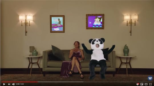 Back on the couch with the disinterested woman, Ed is still in his panda suit. Now, though, we see two framed pictures above him, one of a cat surrounded by very 1990s graphics and the other of Justin Bieber in an inflatable rowing raft.