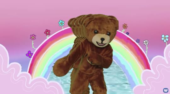 Someone in a Teddy Bear suit dancing in front of a rainbow. There is a weird trailing effect of more bears behind him as he dances.