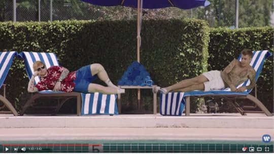 Ed in his pool clothes and Justin shirtless in white shorts are green screened onto poolside lounge chairs.