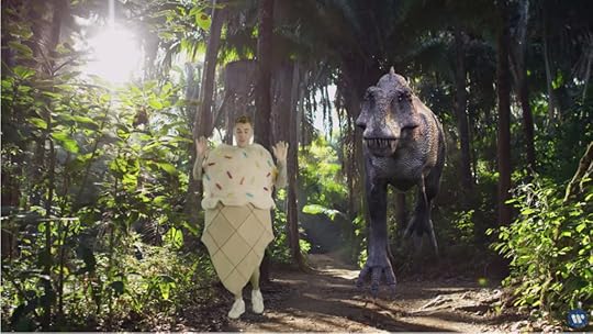 Justin Bieber dancing in his ice cream cone costume in front of a charging T-Rex.