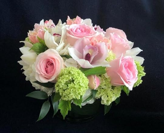 Pink and white spring bouquet of roses, orchid, tulips, and hydrangeas set against dark background.