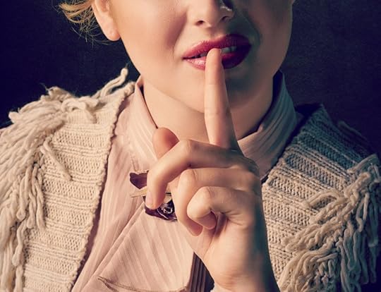 A woman with pink lipstick on putting her finger to her mouth to show she has something she doesn't want to tell.