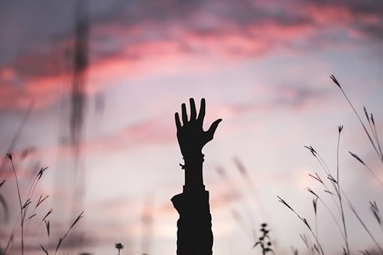 A single hand reaching into the purple and pink skyline.