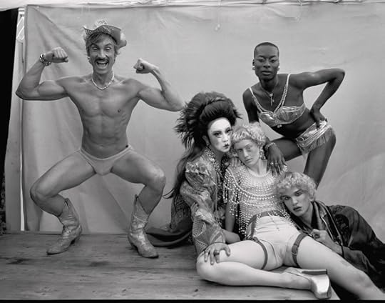 Black-and-white studio photograph of four people in various costumes