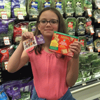girl in grocery store with coupon and box