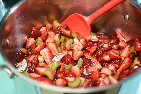 Chopped strawberries and rhubarb mixed with sugar in a stainless steel pot.