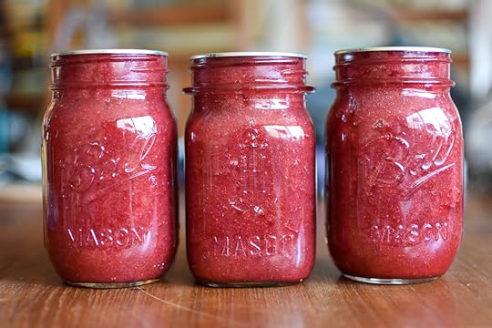 Three jars of low sugar strawberry rhubarb jam sitting in a row on a table