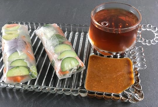 two summer rolls with dipping sauce and a cup of tea on a vintage glass snack set