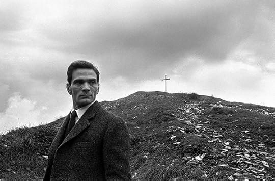 Paolo Di Paolo, Pier Paolo Pasolini on the Monte dei Cocci mountain, Rome, 1955. Horizontal, black-and-white portrait of man in front of a hill with a cross in the background.