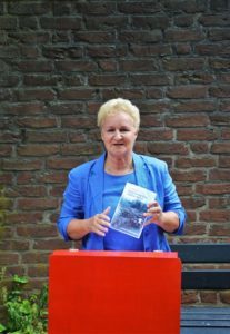 woman standing at a desk holding a book