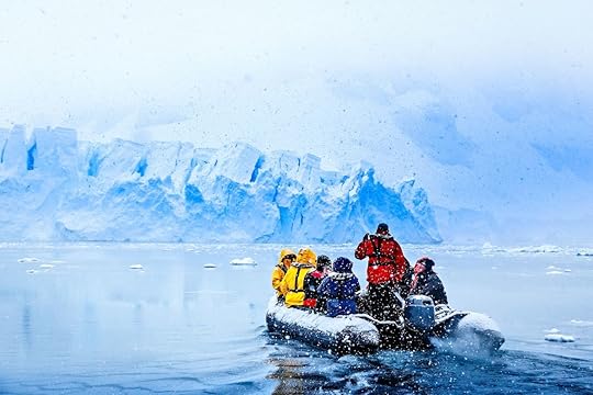 Snowfall over the boat with tourists driving towards a huge blue glacier wall, near Almirante Brown, Antarctic peninsula