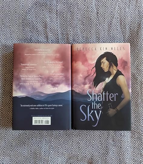 Two finished copies of SHATTER THE SKY, displayed over a blue and white fabric.