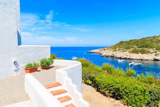 Steps to traditional white house and view of fishing boats on sea in Cala Portinatx bay, Ibiza island, Spain