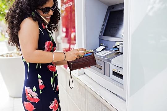 A woman talks on her cellphone as she pulls money out of a local ATM