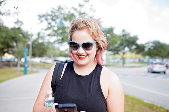 A woman walks down the street as she simultaneously has a good time using her phone.