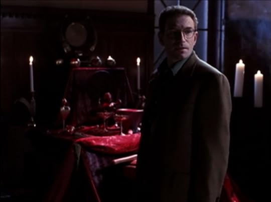 The lawyer guy is standing in front of a nebulous kind of altar thing. It's all red and has bunch of candles around it, and you can kind of make out there are various goblets and metaphysical tools on it. But just barely.