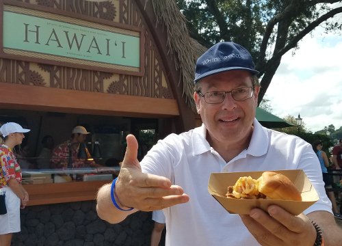 Howard enjoying Kalua Pork Sliders in front of Hawai'i at the Epcot International Food 7 Wine Festival.