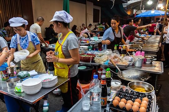 Cooks preparing fast and cheap meals in a big food stall on the street in Silom district