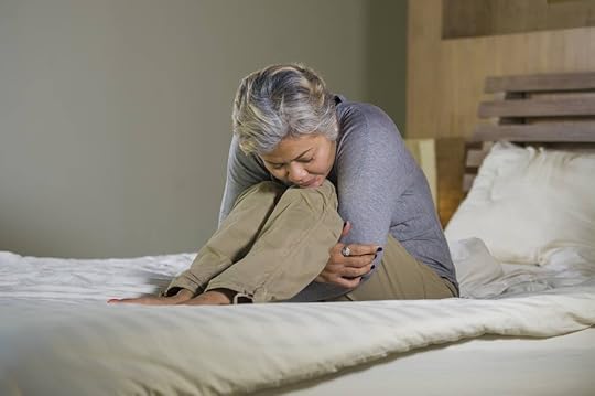 Mature, sad woman sitting on her bed feeling overwhelmed