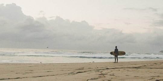 surfer on beach at water's edge holding surfboard