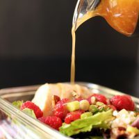 pouring raspberry vinaigrette onto salad