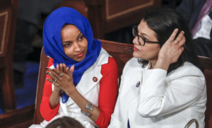 In this Feb. 5, 2019, photo, Rep. Ilhan Omar, D-Minn., left, joined at right by Rep. Rashida Tlaib, D-Mich., listens to President Donald Trump's State of the Union speech, at the Capitol in Washington. A tweet by Omar has sparked a bipartisan backlash, with some accusing her of being anti-Semitic. (AP Photo/J. Scott Applewhite)