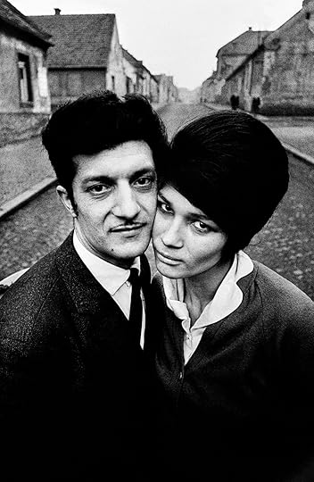 a couple stands in the middle of the street, with their cheeks touching