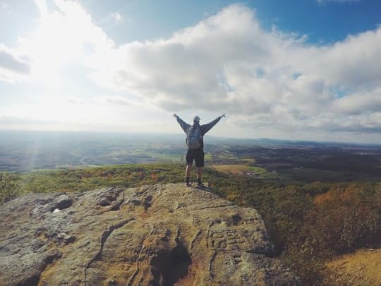 Man stands on a mountain with arms raised