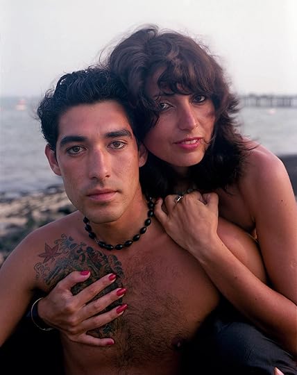 A couple holds each other in front of an ocean landscape