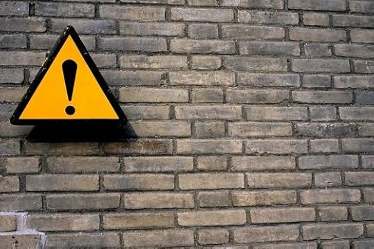 Image: brick wall with sign containing exclamation point