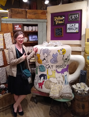 Rachel in Fish's Eddy, standing next to a gigantic mug that says 'Cat Person'.