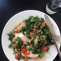 fried eggs on toast piled with veggies