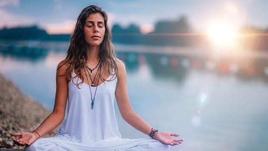 woman in white shirt meditating by a lake