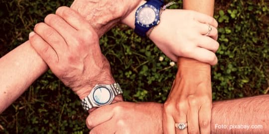 Hände umfassen einander, sodass ein Zusammenhalt von alt und jung symbolisiert wird.