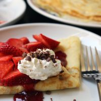 close up of crepe folded and topped with strawberries and cream