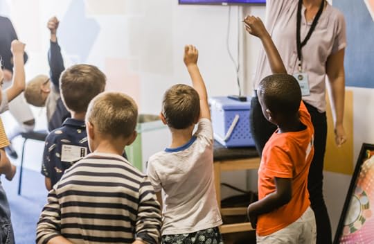 kids raising hands in classroom