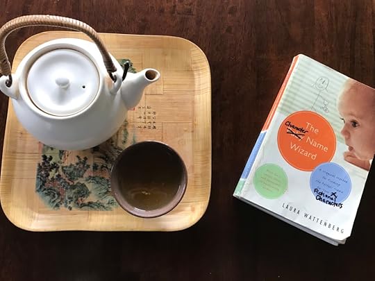 teapot and teacup next to a baby name book, on which the word 